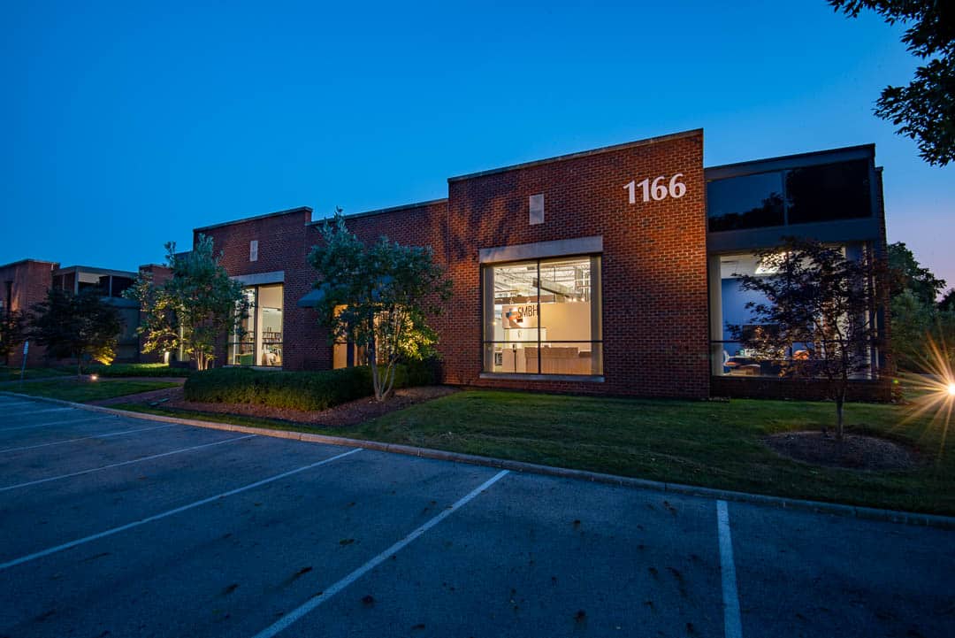 The front exterior of SMBH Headquarters in Columbus, Ohio. A one-story, red brick building with a modern design, at sunset.