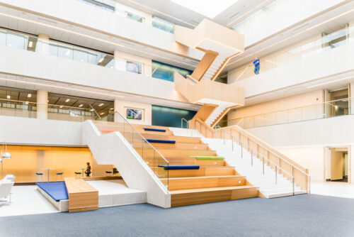 Interior photo of a large space with built in bench seating transitioning between the first and second floor in the OCLC Atrium in Columbus, Ohio.