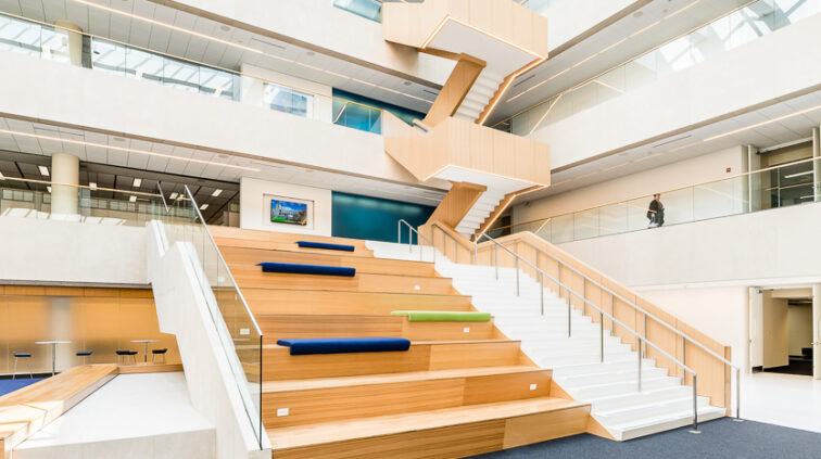 Interior photo of a large space with built in bench seating transitioning between the first and second floor in the OCLC Atrium in Columbus, Ohio.