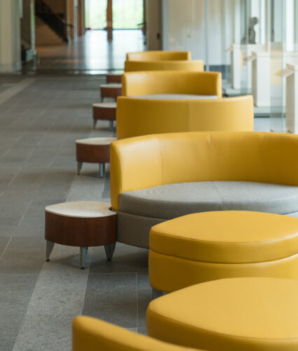 Sets of yellow circular couches in front of large windows letting in lots of light in the Schmidlapp building at the Cincinnati Art Museum.