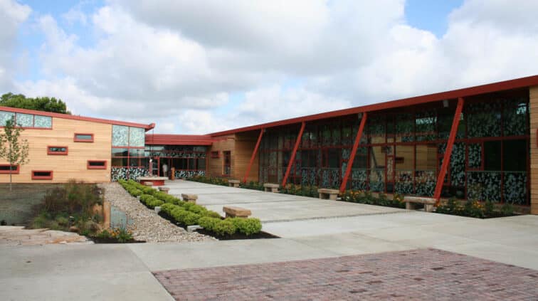 Exterior view of the Grange Audubon Center in Columbus, Ohio. A single-story building with stone exterior and a lobby with glass walls.