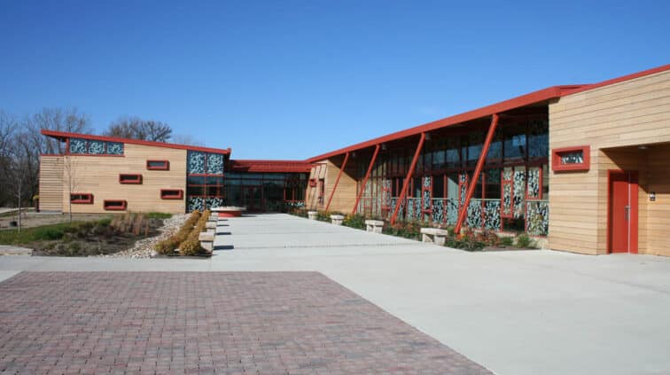 Exterior view of the Grange Audubon Center in Columbus, Ohio. A single-story building with stone exterior and a lobby with glass walls.