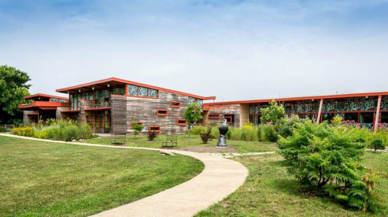 Exterior view of the Grange Audubon Center in Columbus, Ohio. A single-story building with stone exterior and a lobby with glass walls.