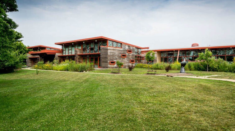 Exterior view of the Grange Audubon Center in Columbus, Ohio. A single-story building with stone exterior and a lobby with glass walls.
