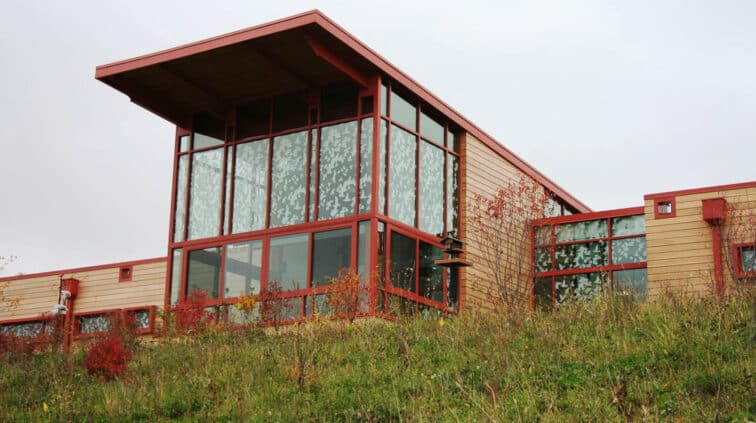 Exterior view of the Grange Audubon Center in Columbus, Ohio. A single-story building with stone exterior and a lobby with glass walls.