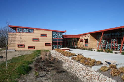 Exterior view of the Grange Audubon Center in Columbus, Ohio. A single-story building with stone exterior and a lobby with glass walls.