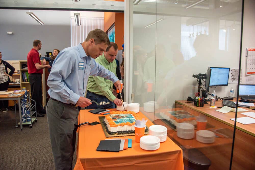 Partners Jon Beier and Joe Noser cut a 50th anniversary sheet cake with a photo of the Long & 3rd Project.