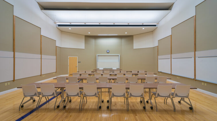 Interior photo of a classroom in Lynn Hall at Hanover College. Features long desks with chairs in front of a back wall that opens like a glass garage door.