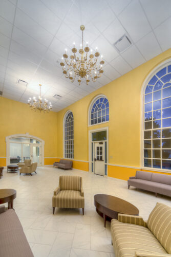 Photo of a common area in Lynn Hall at Hanover College. Features a vaulted ceilings and bright yellow walls with large, arched windows, with comfortable seating for small groups.