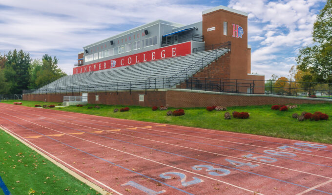 An Exterior image of the Hanover College Stadium, which is mostly brick. Features the starting marks for runners on the track that surrounds the football field.