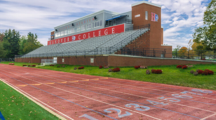 An Exterior image of the Hanover College Stadium, which is mostly brick. Features the starting marks for runners on the track that surrounds the football field.
