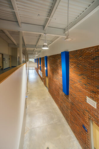 Interior view of a hallway at the Hanover College Stadium, featuring high ceilings and brick work on the right side of the hall.
