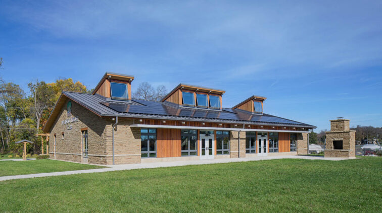 Exterior of Wyandot Lodge at the McKnight Outdoor Education Center, a one-floor building with an exterior of stone and wood with large glass windows.