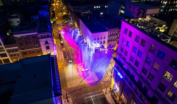 An aerial photo of Janet Echelman's "Current," hanging in downtown Columbus. Composed of different colors of twine and suspended from four different buildings.