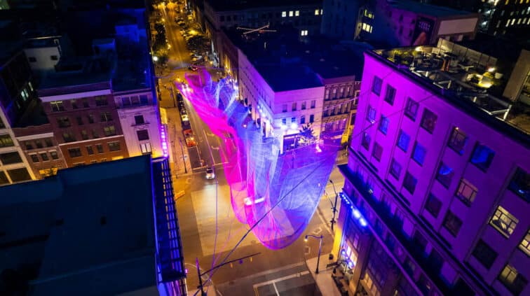 An aerial photo of Janet Echelman's "Current," hanging in downtown Columbus. Composed of different colors of twine and suspended from four different buildings.