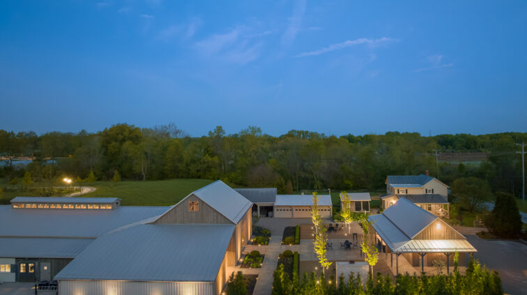 An aerial photo of Jorgensen Farms, featuring multiple buildings, shown at dusk with night lighting.